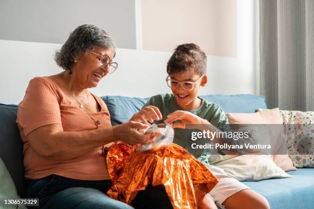 grandma and grandson unwrapping easter egg - chocolate foil stock pictures, royalty-free photos & images