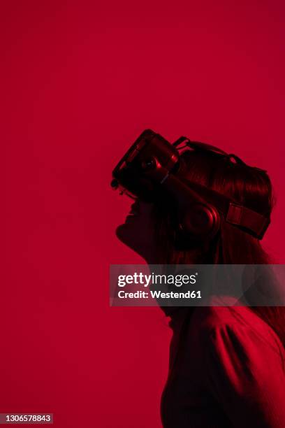 woman using virtual reality headset against red background - top prospects game stockfoto's en -beelden