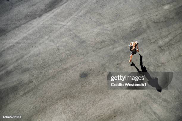 woman running on road during sunny day - asphalt von oben stock-fotos und bilder
