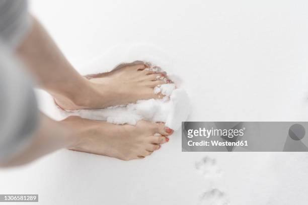 woman standing barefoot in snow - barefoot snow stock pictures, royalty-free photos & images