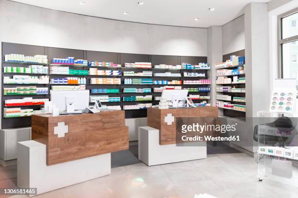 checkout counters against shelves with medicines at pharmacy - farmacia fotografías e imágenes de stock
