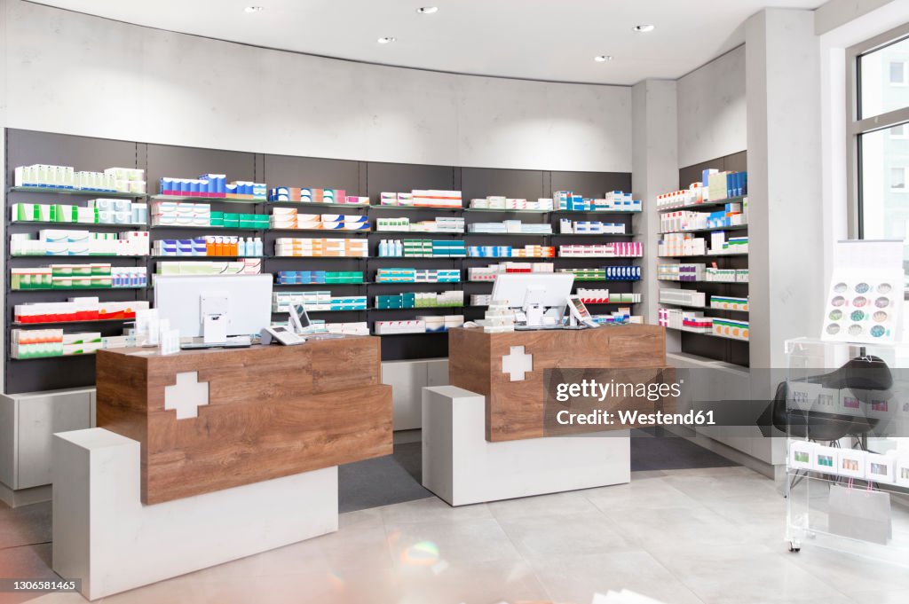 Checkout counters against shelves with medicines at pharmacy