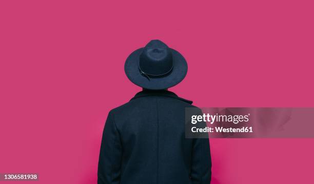 man in hat standing in front of pink background - man back foto e immagini stock