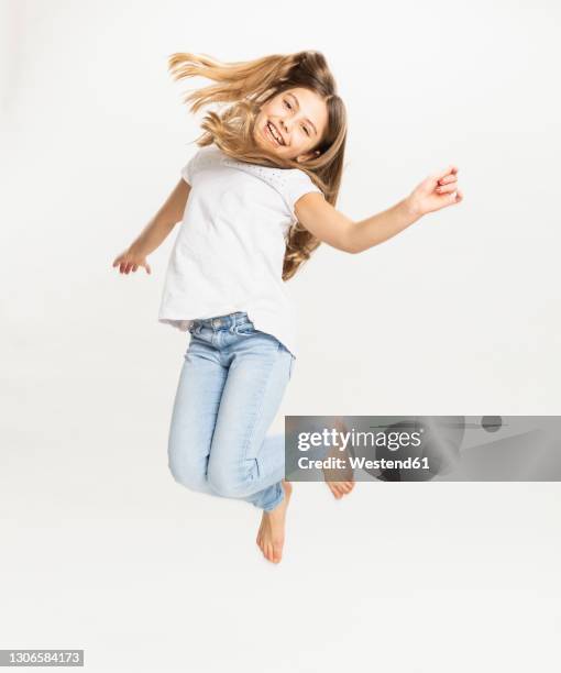 smiling girl jumping against white background - girl jumping stock-fotos und bilder