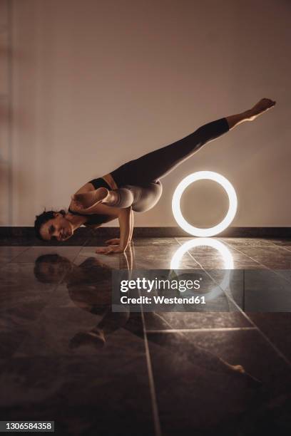 woman practicing kaundinyasana by ring light against wall at home - ring flash foto e immagini stock