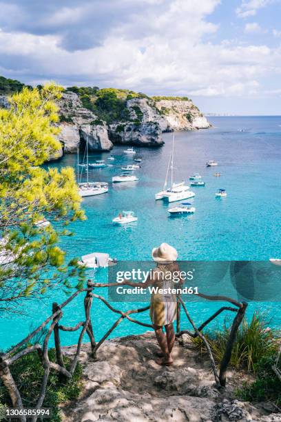 mature woman admiring sea while standing on rock - menorca stockfoto's en -beelden