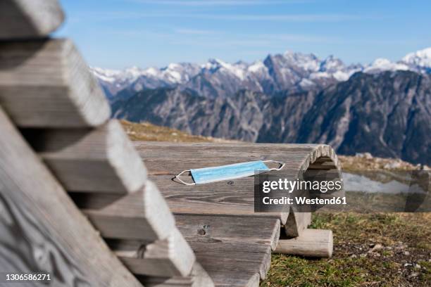 protective face mask on wooden deck chair - wetterfester stuhl stock-fotos und bilder