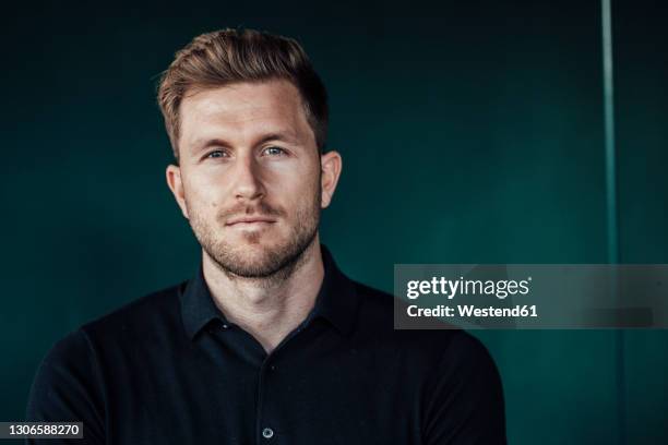 mid adult businessman staring while standing against green background - 30 34 jaar stockfoto's en -beelden