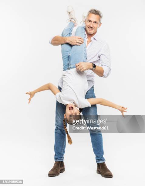 father carrying daughter upside down while standing against white background - family white background stock pictures, royalty-free photos & images