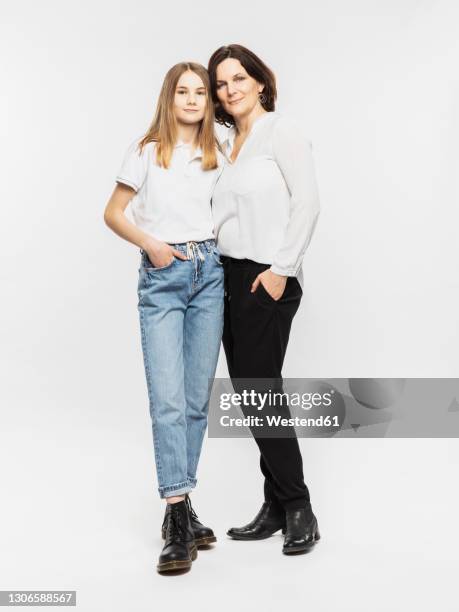 mother standing with daughter against white background - adolescent daughter mother portrait stock-fotos und bilder