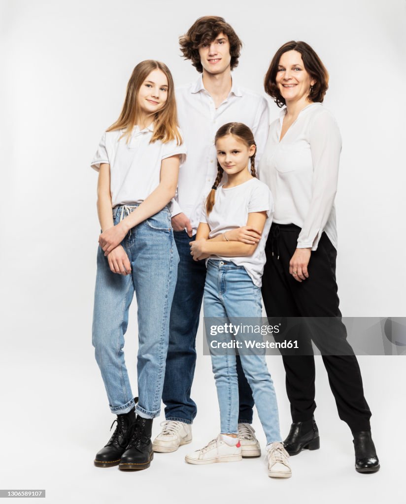 Mother and children standing together in front of white background