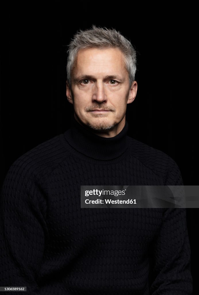 Serious mature man against black background