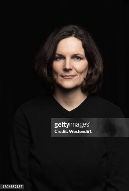 smiling mature woman against black background - black background portrait stockfoto's en -beelden