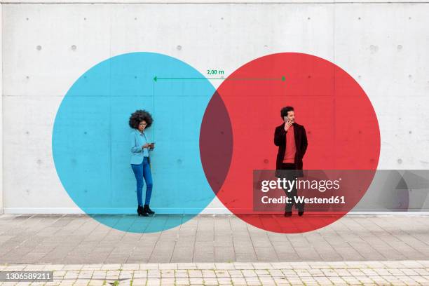 two overlapping circles visualizing social distancing covering man and woman standing outdoors with smart phones in hands - colour separation stock pictures, royalty-free photos & images