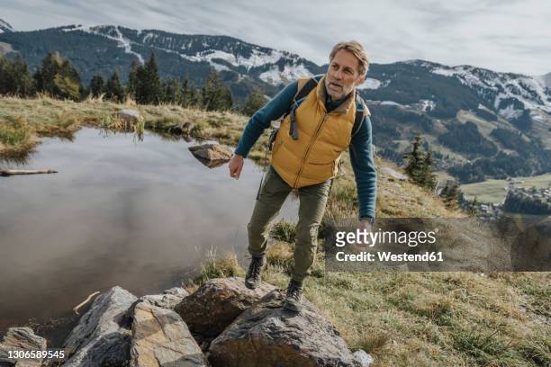 mature man hiking on rock at salzburger land, austria - hiking mature man stock pictures, royalty-free photos & images
