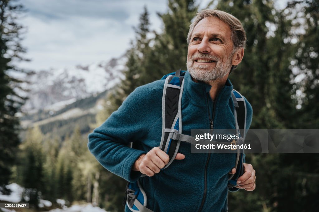 Smiling mature man looking away while hiking in forest at Salzburger Land, Austria