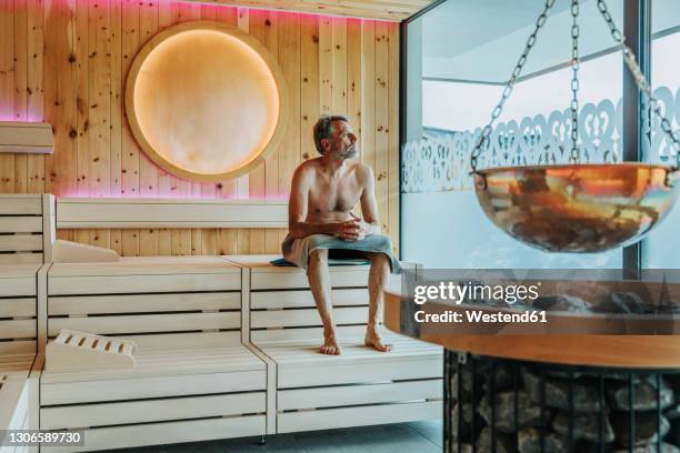 man looking through window while sitting at finnish sauna - sauna ストックフォトと画像