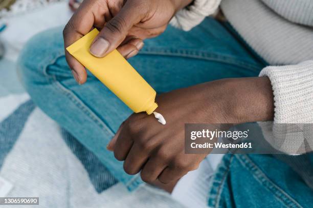 young man applying hand cream through tube - creme tube ストックフォトと画像