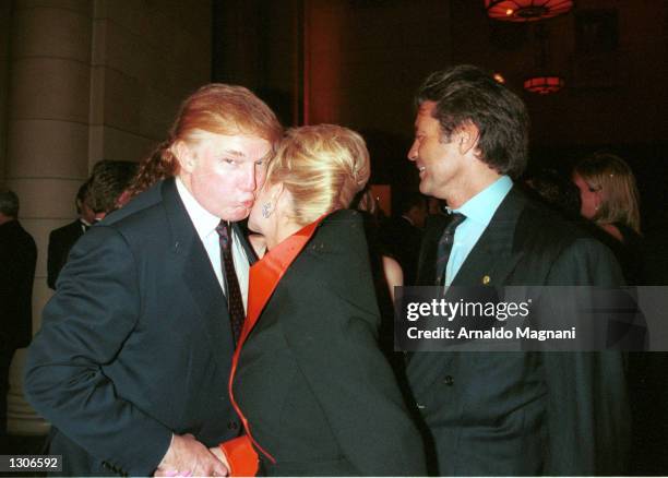 Donald Trump gets a kiss from his ex-wife, Ivana as her boyfriend, Roffredo Gaetani looks on during a benefit auction at Cipriani November 28, 2000...