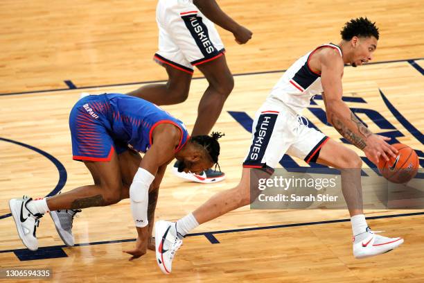 Pauly Paulicap of the DePaul Blue Demons trips battling James Bouknight of the Connecticut Huskies for a loose ball in the first half during the...