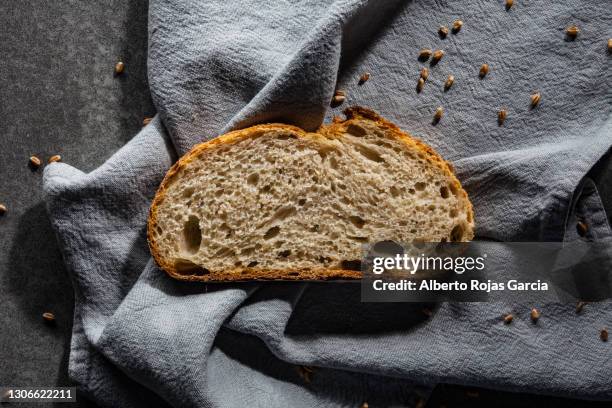 slice of bread on a gray linen napkin - pain au levain photos et images de collection