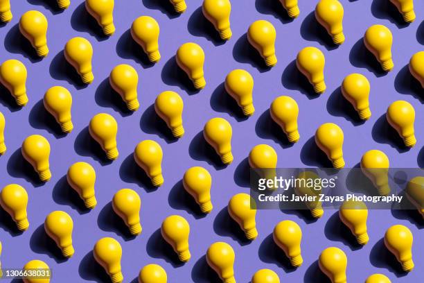 many yellow incandescent light bulbs on purple background - ripetizione foto e immagini stock