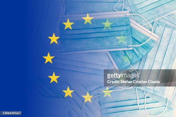 european union flag over face protective masks - european union flag stock-fotos und bilder
