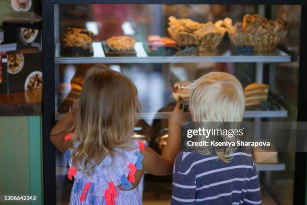 boy and girl in a cafe in front of a shop window are choosing a dessert - stock photo - children restaurant stockfoto's en -beelden