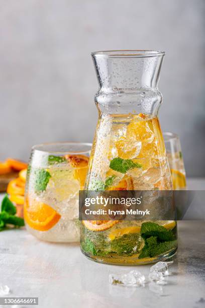 fresh cocktail with crushed ice in glass decanter, mint leaves and divers oranges. summer cold drink concept with copy space - tangerine martini stock pictures, royalty-free photos & images