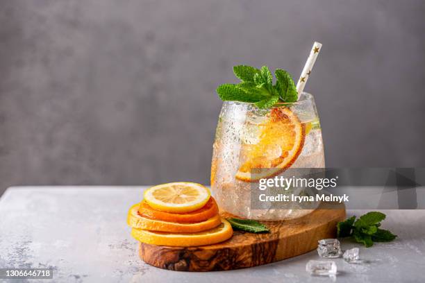 fresh lemonade cocktail with crushed ice, mint leaves and divers oranges. summer cold drink concept with copy space - cocktail fotografías e imágenes de stock