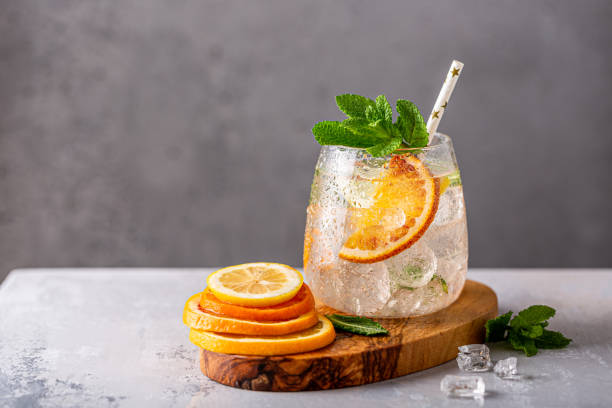 fresh lemonade cocktail with crushed ice, mint leaves and divers oranges. summer cold drink concept with copy space - orange cocktail stock pictures, royalty-free photos & images
