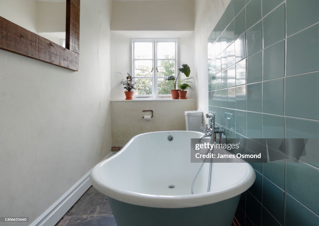 Bathroom with roll top bath and stone floor in a listed period property.