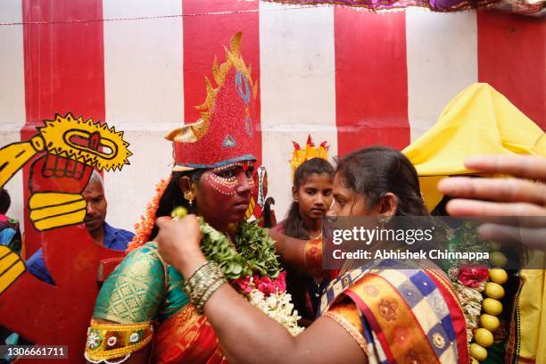 Woman ties a garland of flowers on another woman dresses in the style of a Hindu goddesses as they celebrate Maha Shivaratri on March 12, 2021 in...