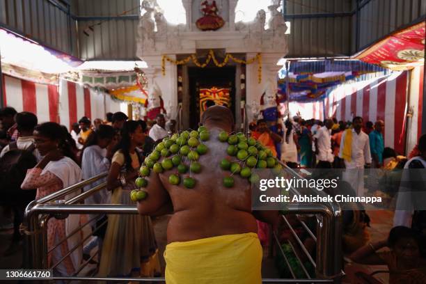 Man with limes pierced to his body offers obeisance to a Hindu god in a temple during Maha Shivaratri on March 12, 2021 in Kaveripattinam, India....