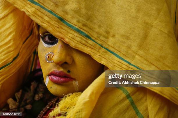 Woman dressed in the style of a Hindu goddess keeps her face partially covered for a ritual during Maha Shivaratri celebrations on March 12, 2021 in...