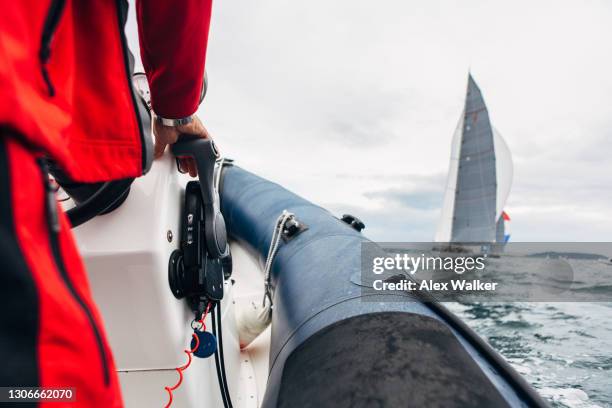 person with hand on throttle of speedboat with sailing yachts in background. - besatzung stock-fotos und bilder