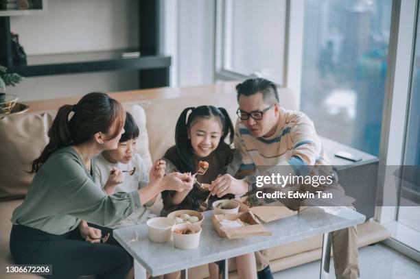 asian chinese young family enjoying take out food in front of tv in living room during weekend - chinese cuisine stock pictures, royalty-free photos & images