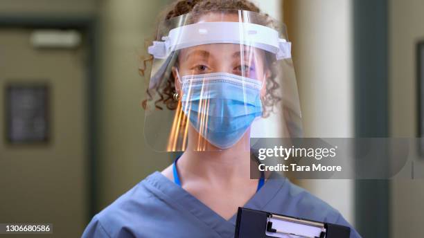 young doctor in scrubs - face shield stock-fotos und bilder