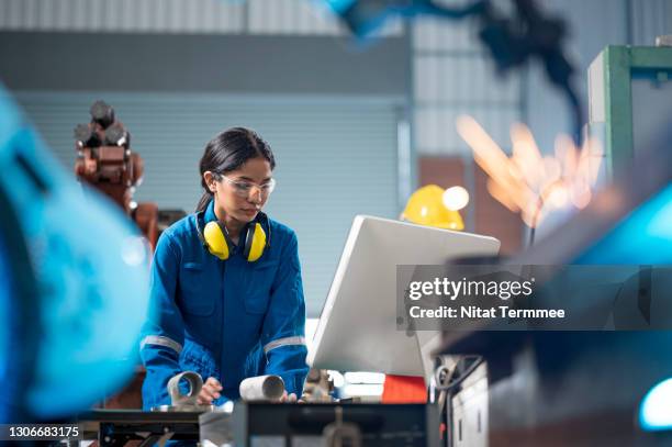female industrial engineer working on desktop computer in robotic welding testing area of research and development in automobile industry. productivity improvement concepts. - usine photos et images de collection