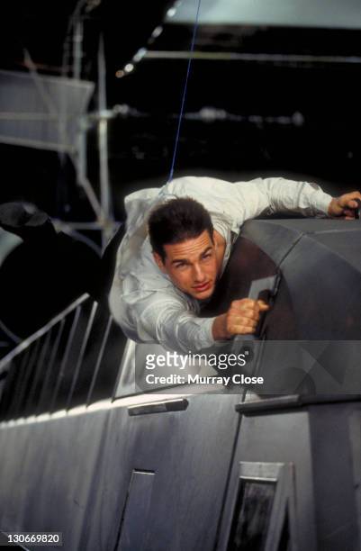 American actor Tom Cruise as Ethan Hunt, filming a scene for the movie 'Mission: Impossible' at Pinewood Studios, 1995. In this scene he clings to a...