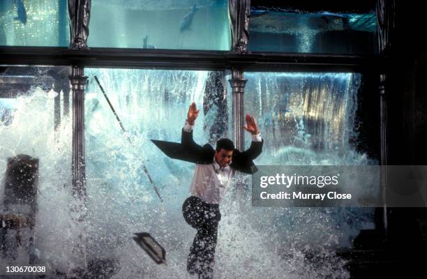American actor Tom Cruise as Ethan Hunt, escaping through the collapsing aquarium in a restaurant, in a scene from the film 'Mission: Impossible',...