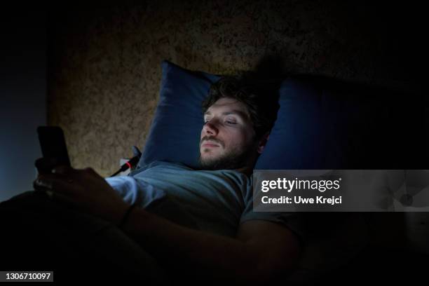 man in bed on smartphone - sleepless stock pictures, royalty-free photos & images