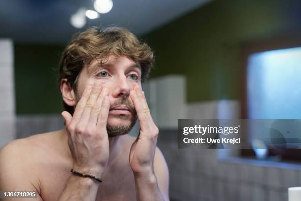 man applying creme on his face - tired bildbanksfoton och bilder