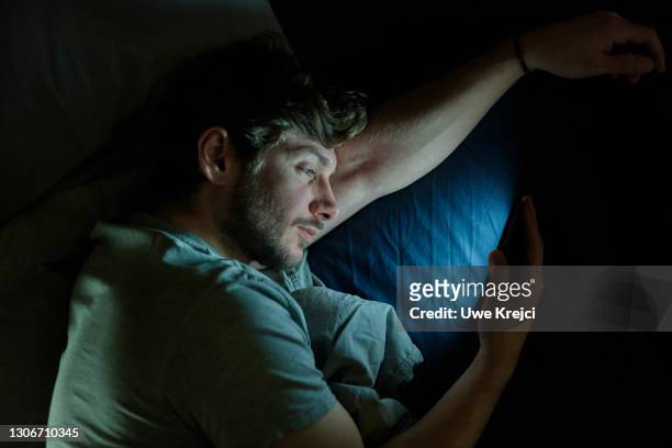 man in bed on smartphone - good night imagens e fotografias de stock