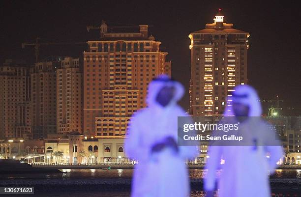 Newly-constructed apartment buildings at a development called The Pearl loom beind two Arab men wearing dishdashas on October 27, 2011 in Doha,...