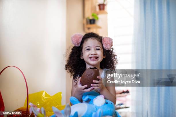 cute little child. girl eating chocolate easter egg - chocolate egg stock pictures, royalty-free photos & images
