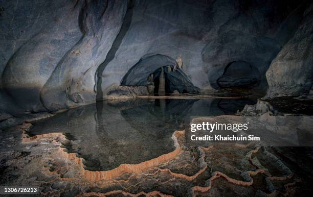 reflection of shallow pond inside a massive cave - dim sim stock pictures, royalty-free photos & images