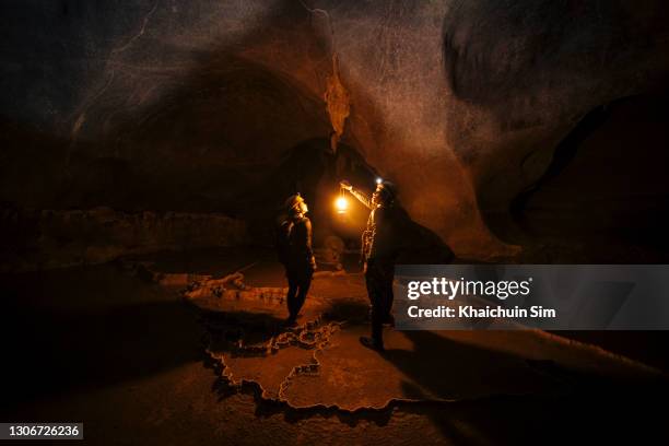 two explorers inside a massive cave - cave stockfoto's en -beelden