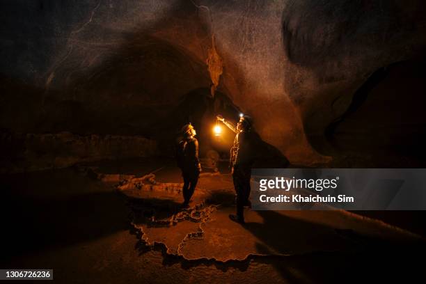two explorers inside a massive cave - caves bildbanksfoton och bilder