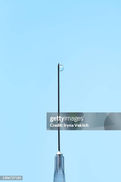corona virus covid-19 medical vaccine concept with disposable syringe with drop of fluid of vaccine on needle on blue background. - acupuncture needle stock pictures, royalty-free photos & images